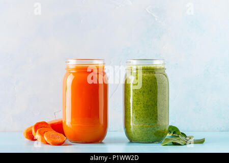 Arancione/verde frullati colorati / succo in un recipiente su uno sfondo blu. Foto Stock