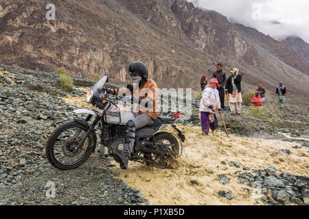 Valle di Nubra, India - 29 Giugno 2017: ciclista attraversando il fiume che scorre dal ghiacciaio di fusione in Himalaya, regione del Ladakh, India Foto Stock