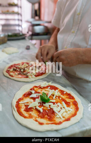 La preparazione di classic pizza Margherita in pizzeria tradizionale a Napoli, Italia. Messa a fuoco selettiva Foto Stock