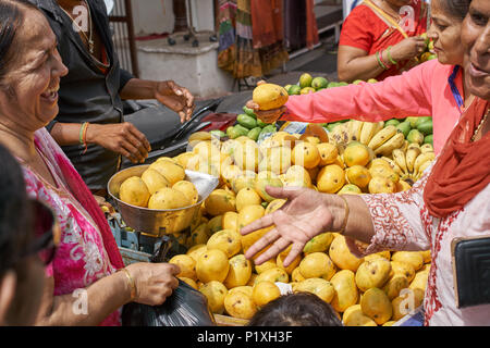 Le donne ridere mentre l'acquisto di mango fresco frutta presso un fornitore in Pushkar, Rajasthan. Foto Stock