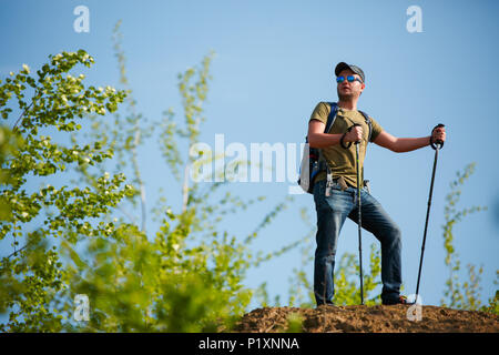 Immagine dell uomo con zaino e bastoni da passeggio sulla collina Foto Stock