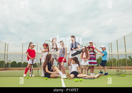 Ritratto di un gruppo di ragazze come i giocatori di tennis holding racchetta da tennis contro erba verde del tribunale aperto Foto Stock