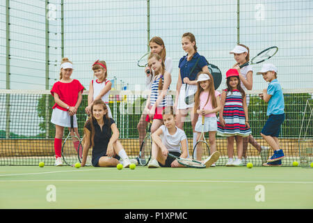 Ritratto di un gruppo di ragazze come i giocatori di tennis holding racchetta da tennis contro erba verde del tribunale aperto Foto Stock