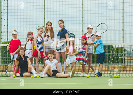 Ritratto di un gruppo di ragazze come i giocatori di tennis holding racchetta da tennis contro erba verde del tribunale aperto Foto Stock