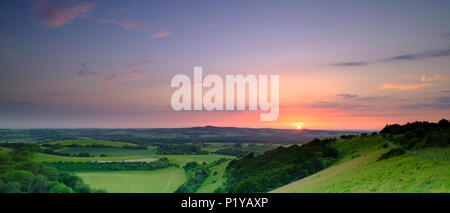 Drammatica e colorato a metà estate tramonto su Beacon Hill dal vecchio Winchester Hill nel South Downs National Park vicino a Warnford, Hampshire, Regno Unito Foto Stock