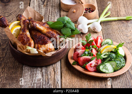 Pollo arrosto cosce di pollo disossate in vaso di ceramica e verdure fresche sulla tavola in legno rustico, cibo preferito Foto Stock