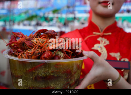 (180613) -- XUYI, 13 giugno 2018 (Xinhua) -- un venditore visualizza una ciotola di astaci durante un grande banchetto di gamberi in Xuyi, est cinese della provincia di Jiangsu, 13 giugno 2018. Più di 50.000 residenti e turisti hanno preso parte alla festa qui mercoledì. Gamberi di fiume-industrie correlate in Cina ha visto la forte crescita dello scorso anno come uscita totale di schizzata da 83,15 percento a 268.5 miliardi di yuan (42 miliardi di dollari) nel 2017, detto un rapporto rilasciato martedì. Un totale di 1,13 milioni di tonnellate di gamberi di fiume sono state sollevate lo scorso anno, con le province di Hubei, Anhui, Hunan, Jiangsu Jiangxi e come i grandi produttori. Foto Stock