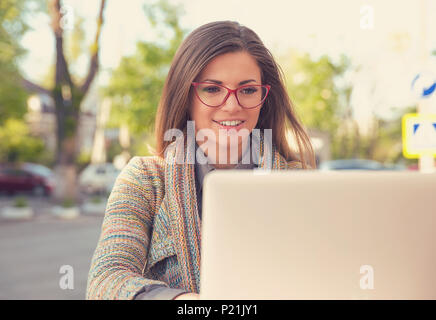 Attraente giovane donna utilizzando laptop al di fuori Foto Stock