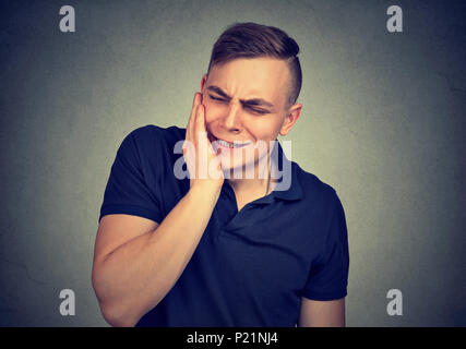 Il mal di denti. Frustrati giovane uomo nel dolore toccando la guancia e tenere gli occhi chiusi Foto Stock