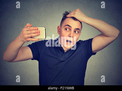 Ritratto sconvolto l uomo sensazione di testa, sorpreso egli è perdita di capelli isolati su sfondo grigio. Negative le espressioni facciali, emozione Foto Stock