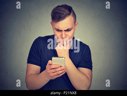 Clueless dumb guy avendo problemi con il suo smartphone. Complicato il concetto di tecnologia Foto Stock