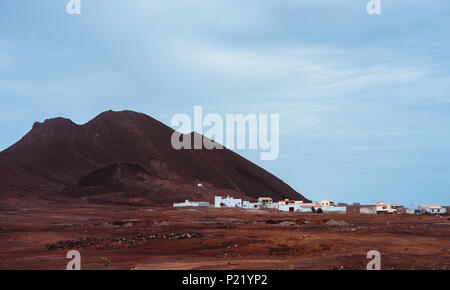 Villaggio locale Calhau ai piedi del cratere vulcanico. Unico come il marziano a secco di roccia rossa spiccano dal deserto arido terreno. Capo Verde - Sao Vicente Isola Foto Stock