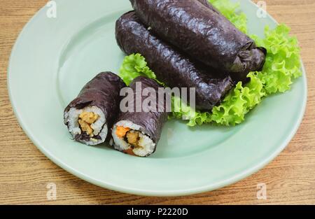 La cucina giapponese, Vagetarian tradizionale di riso giapponese maki sushi Roll roba con tofu e carote avvolte in Nori alghe servita sulla quercia verde. Foto Stock