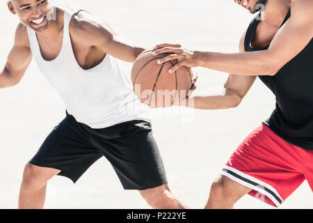 Ritagliato colpo di uomini in abbigliamento sportivo giocare a basket insieme Foto Stock