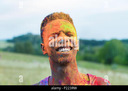 Ritratto di felice african american uomo con polvere sul viso durante Holi festival Foto Stock