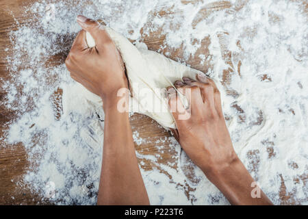 Ritagliato colpo di mani impastare la pasta su un tavolo di legno top Foto Stock