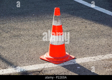 Cono di traffico, con bianco e strisce arancioni su grigio asfalto, Foto Stock