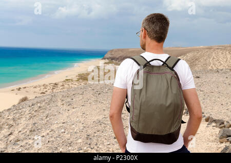 Un turista con lo zaino ammirando la vista sul mare della spiaggia dell'oceano di Sotavento Foto Stock