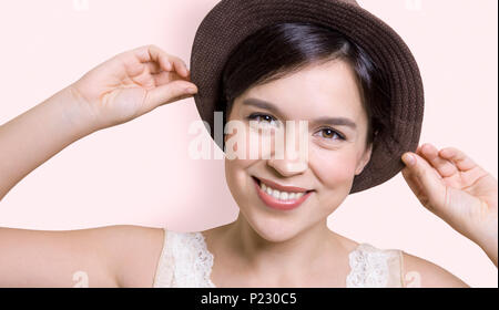 Giovane donna attraente tenendo il suo cappello e sorridente Foto Stock