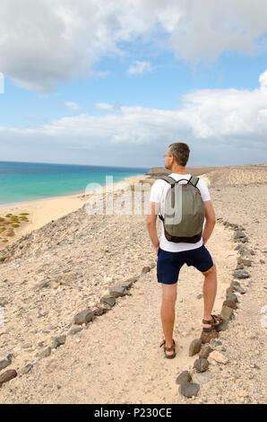 Un turista con lo zaino ammirando la vista sul mare della spiaggia dell'oceano di Sotavento Foto Stock