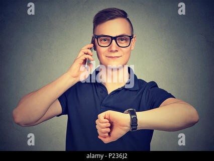 Business e tempo di concetto di gestione. Uomo con orologio da polso, parlando al telefono mobile di essere in tempo per la riunione. Foto Stock