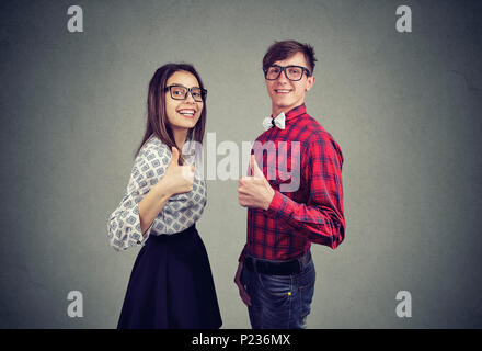 Vista laterale del contenuto di giovane uomo e donna che mostra Thumbs up essendo in un grande rapporto di sorridere alla telecamera. Foto Stock