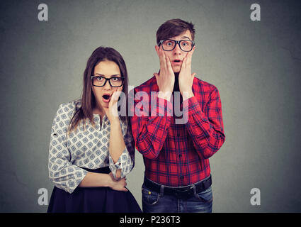 Spaventata nervosi l uomo e la donna che guarda con largamente aperto bocca in telecamera, stando in piedi a fianco a fianco. Divertenti coppia sorpreso vedendo qualcosa di strano Foto Stock