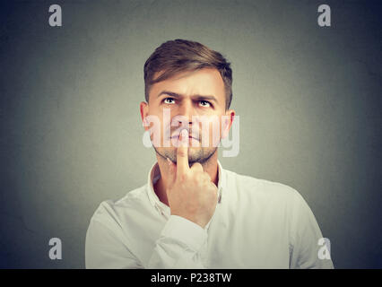 Bello Casual Uomo in camicia bianca toccando le labbra con le dita e il pensiero sul problema cercando. Foto Stock