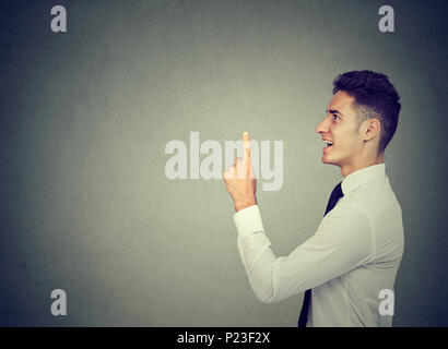 Eureka! Giovane uomo d affari con un dito verso l'alto isolato su sfondo grigio Foto Stock