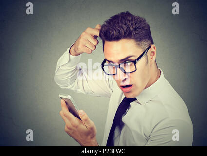 Scioccato uomo sensazione di testa, sorpreso egli è la perdita di capelli, receding hairline isolato su sfondo grigio. Foto Stock