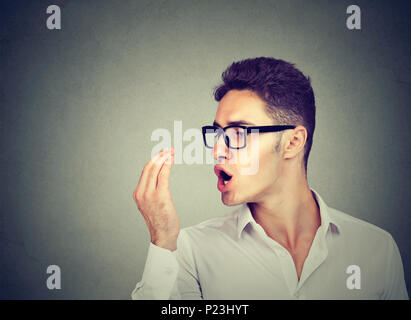 Giovane uomo in vetri controllo del respiro con la sua mano. Foto Stock