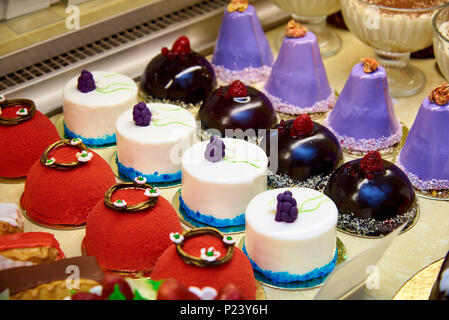 Le righe di una varietà di dessert luminoso sulla vetrina. Foto Stock