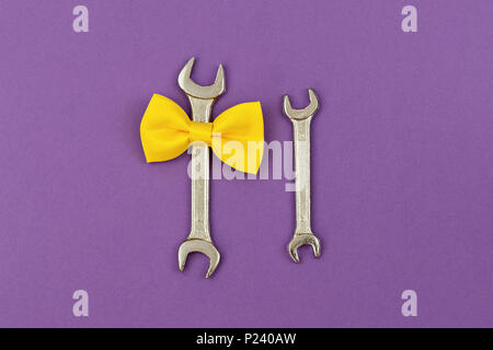 Chiave a due grandi e piccoli con cravatta gialla bow su sfondo viola. Biglietto di auguri per celebrare il Padre, compleanno e il giorno di San Valentino, spazio di copia Foto Stock
