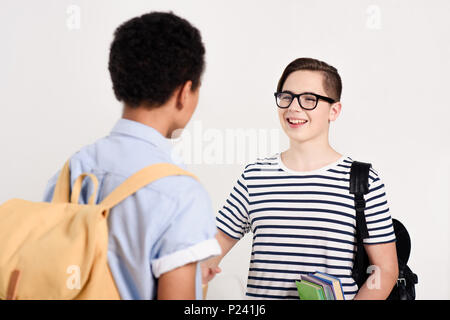 Multiculturale ragazzi teen con sacchetti parlando isolato su bianco Foto Stock