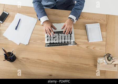 Vista dall'alto di imprenditore digitando su laptop al lavoro in ufficio moderno Foto Stock