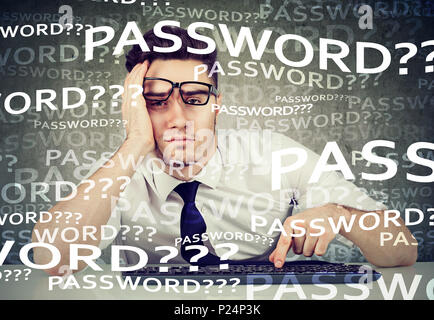 Disperata giovane uomo d affari cercando di accedere al suo computer password dimenticata Foto Stock