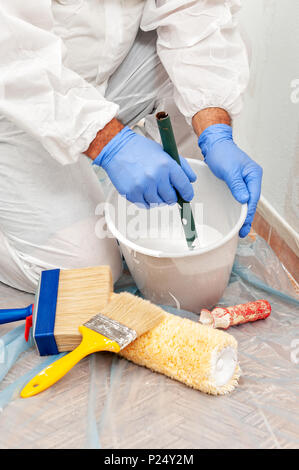 Casa pittore al mix di lavoro di vernice e di acqua in un contenitore Foto Stock