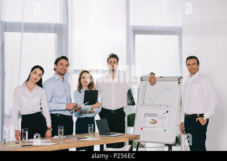 Ritratto di gente di affari dopo la formazione aziendale permanente al bordo bianco in office Foto Stock