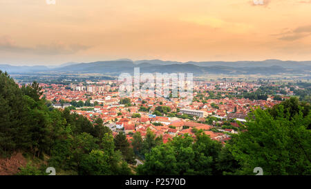 Ora d'oro cielo soleggiato Pirot città in Serbia e il verde degli alberi in primo piano Foto Stock