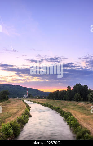 Vista verticale del moto sfocata Nisava fiume di Pirot e distante il vecchio stabilimento durante la vivace, burning sunset Foto Stock