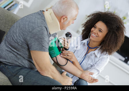 L'infermiera la misura della pressione del sangue di senior a casa Foto Stock