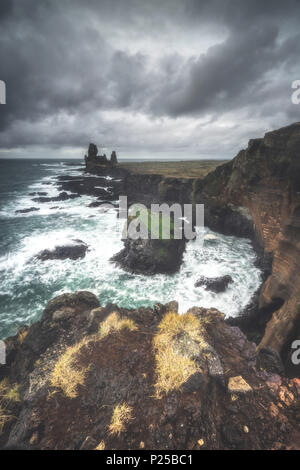 Bird rock e alle circostanti scogliere di basalto. Londrangar, Snaefellsness National Park, Western Islanda, Europa Foto Stock