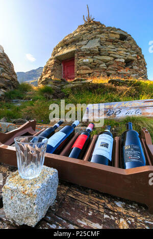 Esposizione di vino e il vetro con la tradizionale cantina in background. Sassal Mason, Passo Bernina, Val Poschiavo, Grigioni, Svizzera. Foto Stock