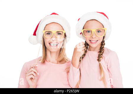 Felice madre con la figlia in cappelli di Babbo Natale e il partito di cartone bicchieri sul Natale, isolato su bianco Foto Stock