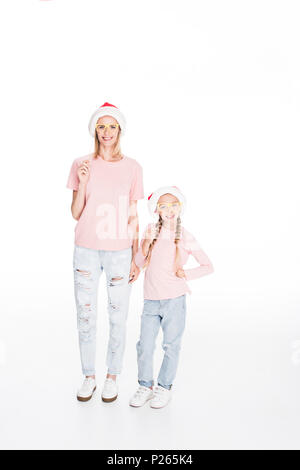 Giovane madre e figlia indossando cappelli di Babbo Natale e trattenere parti di cartone bicchieri, isolato su bianco Foto Stock