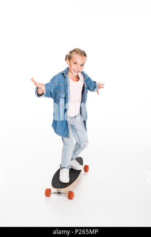 Bambino in denim oversize shirt in equilibrio su un longboard, isolato su bianco Foto Stock