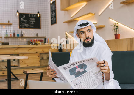 Bel giovane imprenditore musulmano con il giornale in cafe Foto Stock