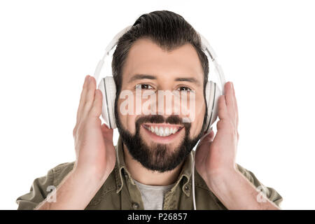 Sorridente uomo barbuto ascoltando musica con le cuffie, isolato su bianco Foto Stock