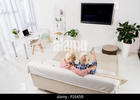 Coppia senior di guardare la televisione sul lettino accogliente a casa Foto Stock