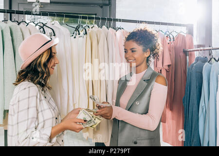Giovani donne eleganti Conteggio contanti in negozio di abbigliamento Foto Stock